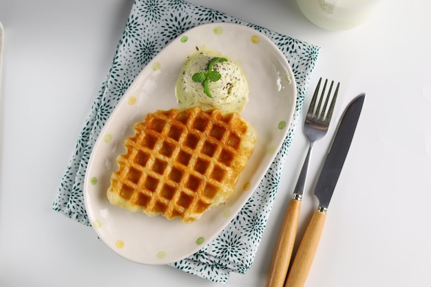 Croissant Waffle or Croffle with avocado ice cream served in the oval plate with spoon and fork