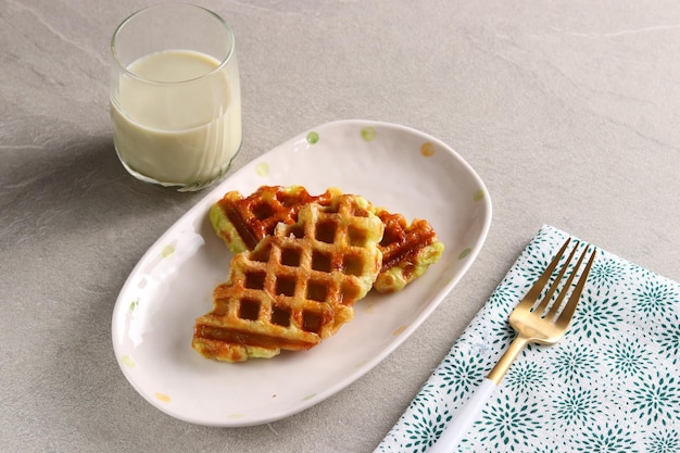 Croissant Waffle or Croffle with a glass of matcha milk served in the oval plate with fork.