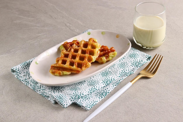 Croissant Waffle or Croffle with a glass of matcha milk served in the oval plate with fork.