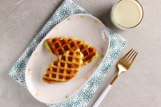 Croissant Waffle or Croffle with a glass of matcha milk served in the oval plate with fork.