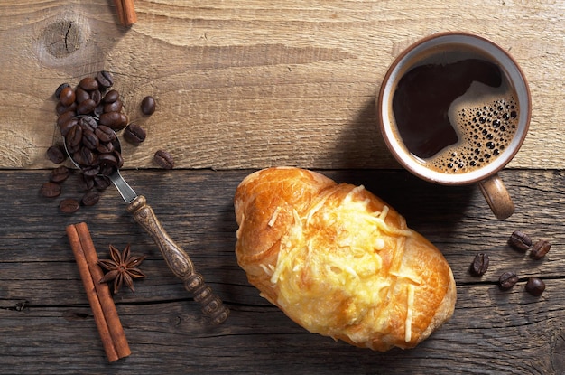 Croissant with cheese and cup of hot coffee on old wooden background top view