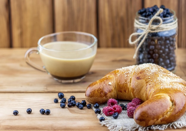 Croissant with fresh berries and a cup of coffee with milk