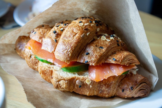 Croissant with sesame salmon and cucumber on the table selective focus closeup