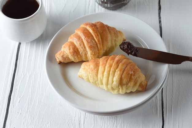 croissantFreshly baked croissants on a tray with a small jar of jam for breakfast