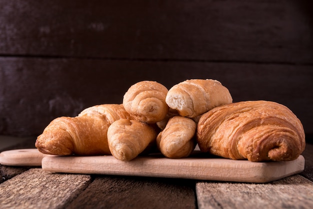 Croissants on board on wooden background. Rustic style.