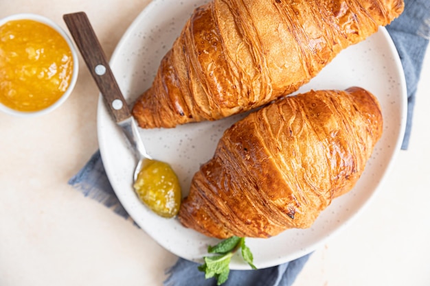 Croissants on ceramic plate with jam light concrete background