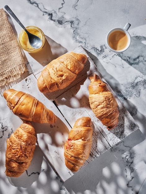 Croissants and coffee on white table