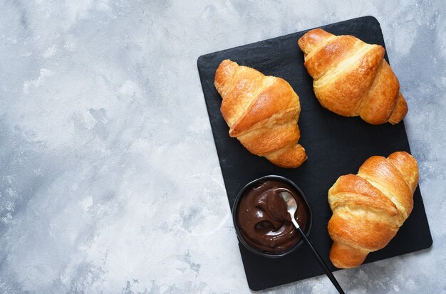 Croissants on a stone board on a concrete background. View from above.