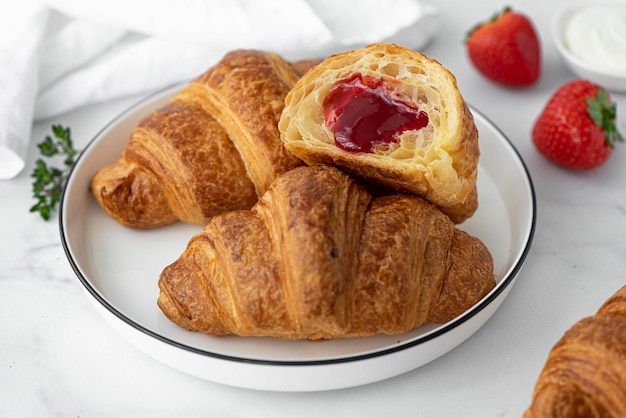 Croissants stuffed with strawberry jam on a white plate