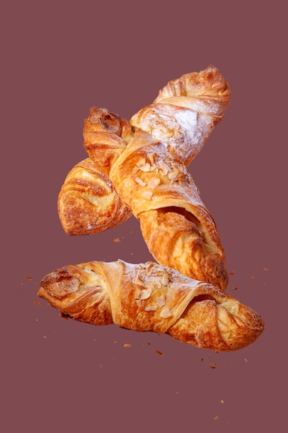 Croissants with almonds fly on a burgundy background