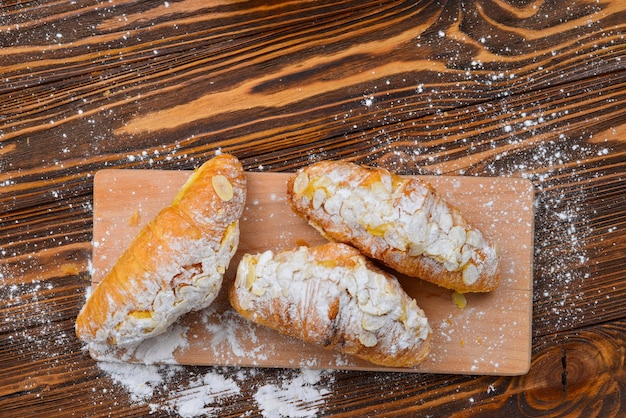 Croissants with almonds and tea on a wooden table