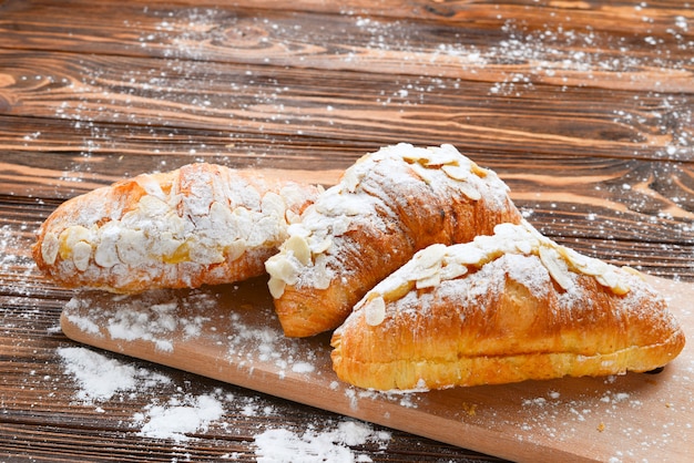 Croissants with almonds and tea on a wooden table.