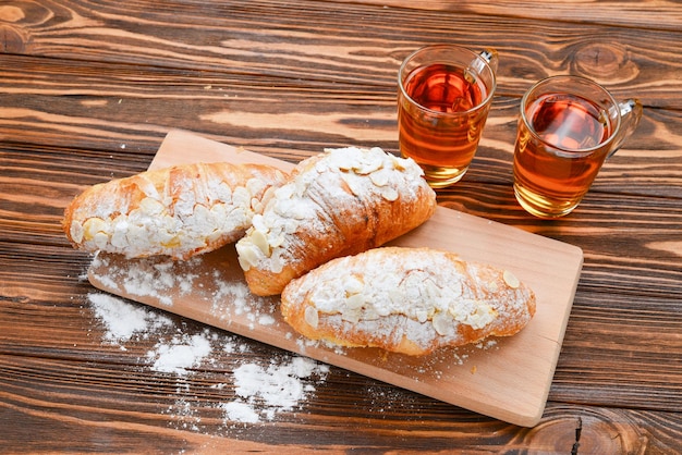 Croissants with almonds and tea on a wooden table