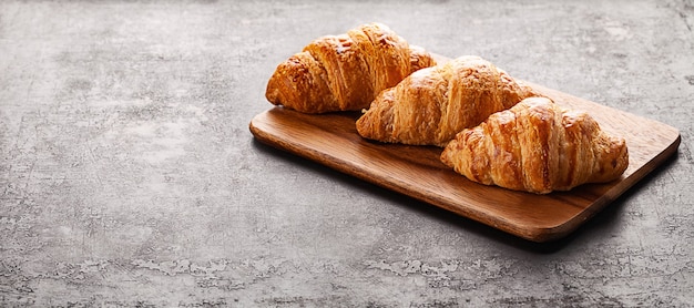 Croissants on  on wooden board lying on old rustic background