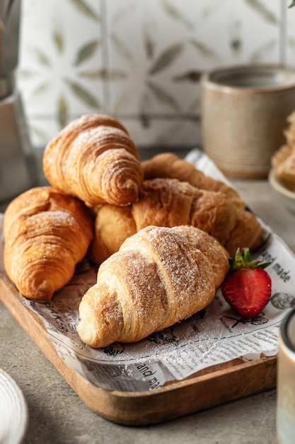 Croissants on wooden tray with berries and coffee for breakfast with tile background