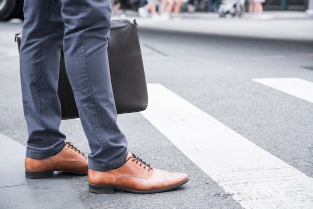 Crop businessman standing near crosswalk