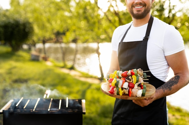 Crop cheerful chef with skewers