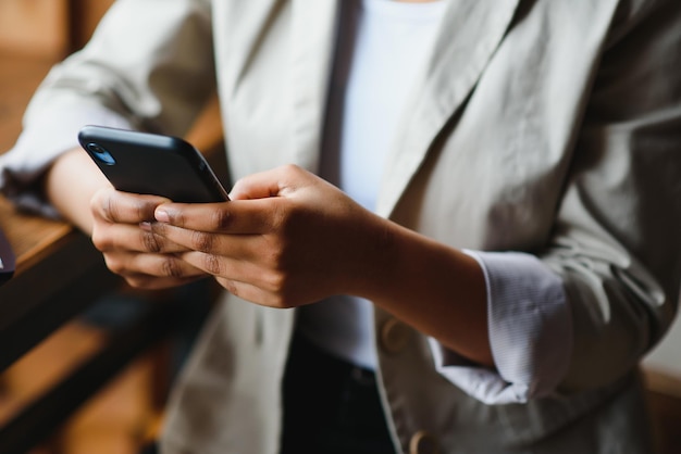 Crop close up of African American woman hold cellphone text message online on gadget. Ethnic biracial female use smartphone browse surf wireless internet on device. Technology, communication concept.