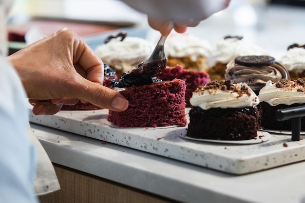 Photo crop cook smearing jam on cakes in kitchen