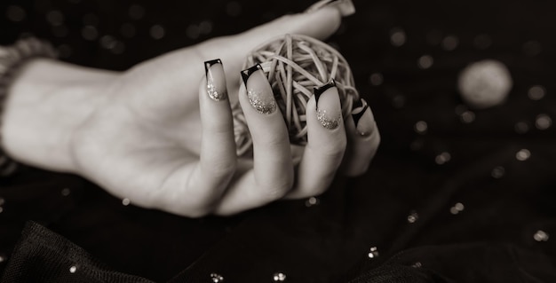 Crop girl's hand with manicure Unrecognizable female showing nail polish on black background