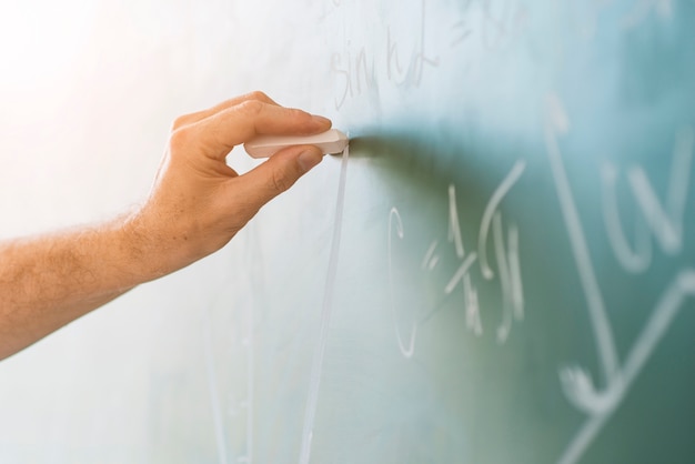 Crop hand chalking on blackboard