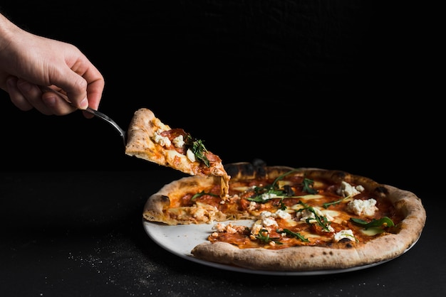 Crop hand taking slice of pizza