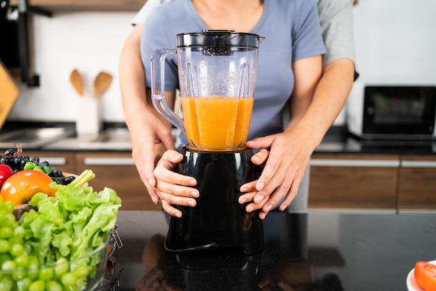 Crop image of happy Asian couple enjoy using blender machine for making healthy vegan smoothie on the kitchen counter Couple making vegan smoothie together at home for a healthy lifestyle