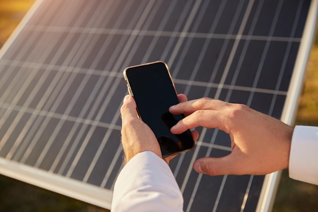 Crop man using smartphone on solar farm