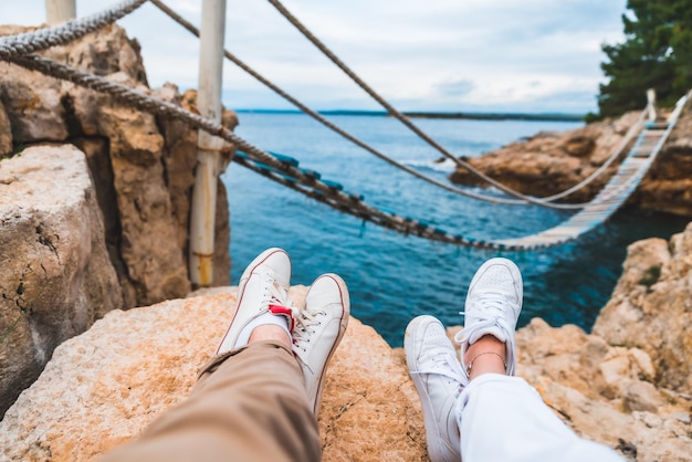 Crop picture couple legs at cliff suspension bridge on background copy space