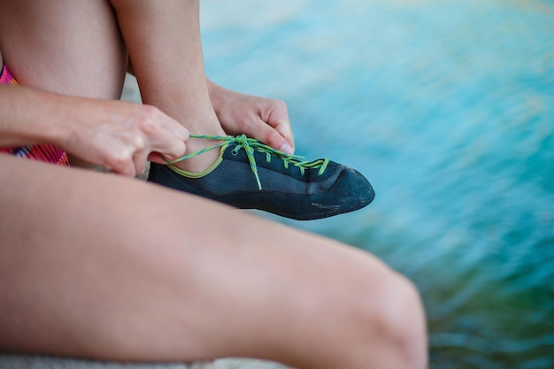 Crop unrecognizable woman tying Feet of Cat rock climbing sneakers