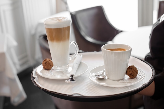 Crop waiter with coffee on tray