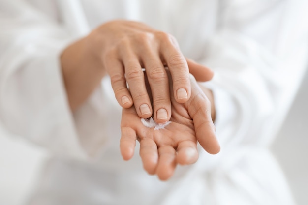 Cropped of adult lady using hand cream after shower