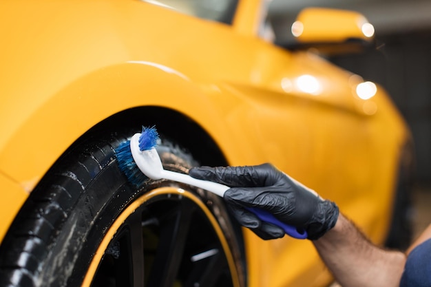 Photo cropped close up image of male hands in black protective gloves cleaning wheels tires