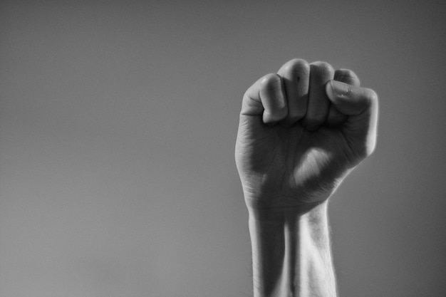 Cropped hand clenching fist against gray background