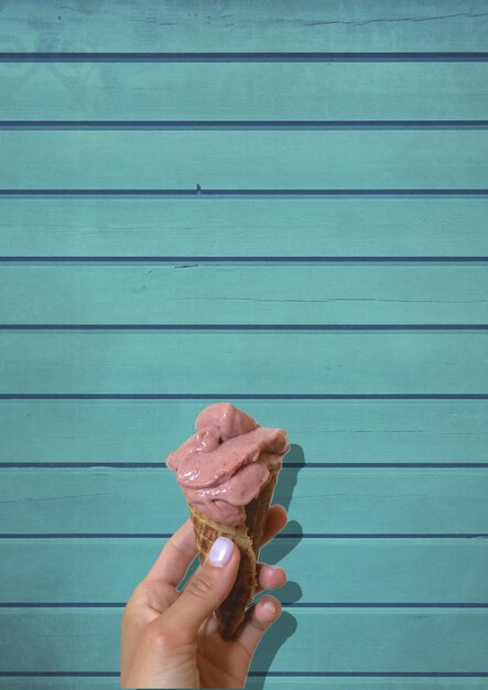 Photo cropped hand holding ice cream cone on wood