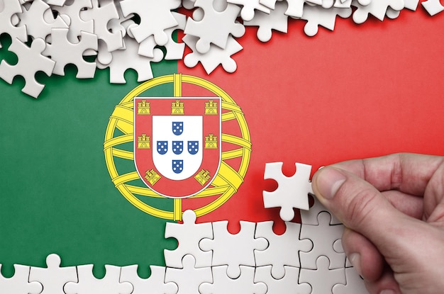 Photo cropped hand holding puzzle piece over portuguese flag