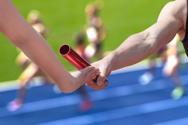 Cropped hand of man passing relay baton to partner