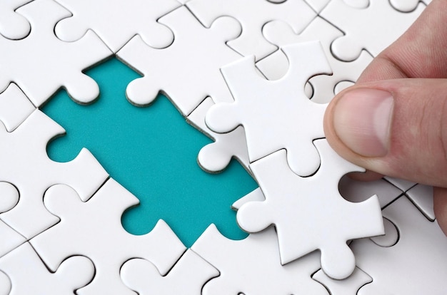 Photo cropped hand of man playing jigsaw puzzle on table