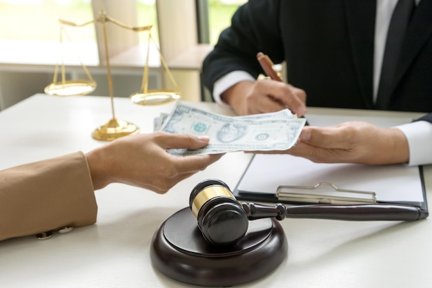 Cropped hand of person giving bribe to lawyer signing document on table