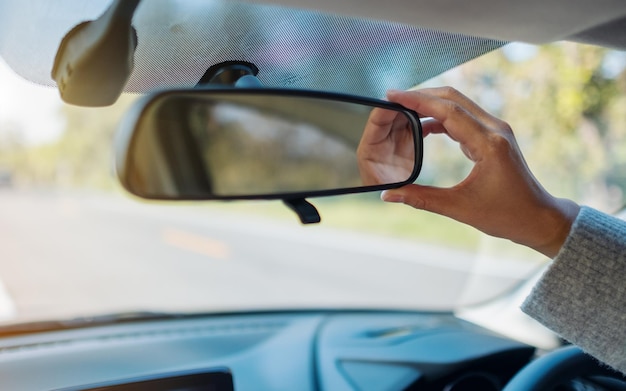 Photo cropped hand of woman adjusting rear-view mirror in car