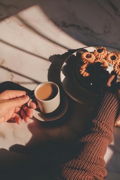 Photo cropped hand of woman holding coffee on table