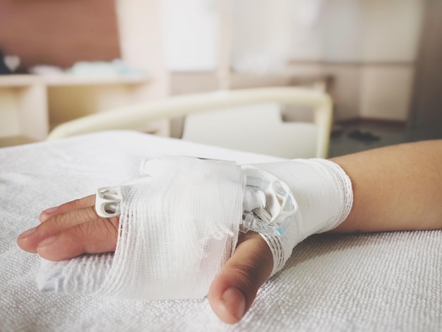 Photo cropped hand of woman with iv drip on bed at hospital