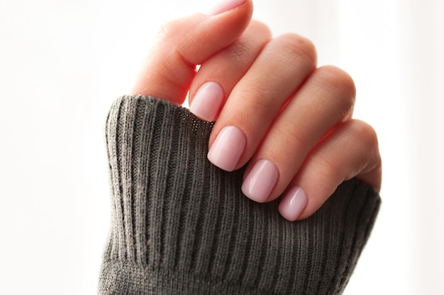 Cropped hand of woman with pink painted nails against white background