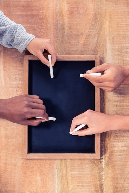 Cropped hands of business people writing on slate at creative office