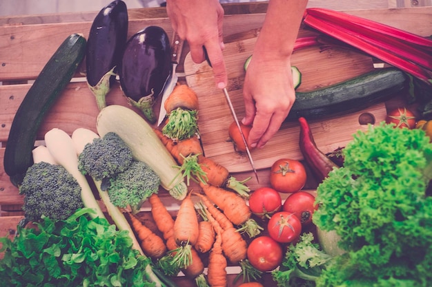 Photo cropped hands of person cutting vegetables in kitchen at home