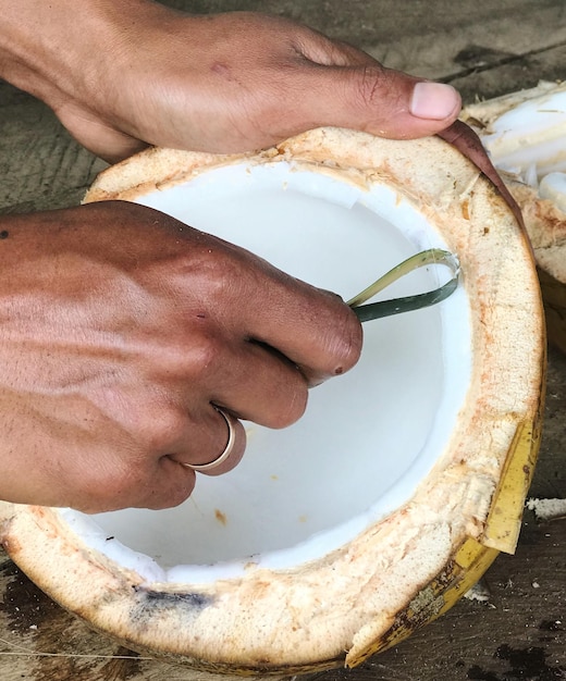 Photo cropped hands of person holding coconut on table