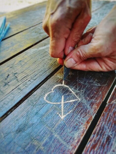 Photo cropped hands of person making heart shape on wooden table