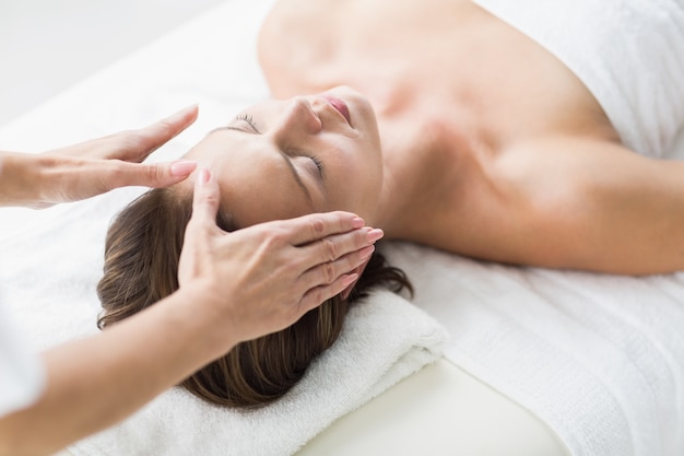 Cropped hands of therapist performing reiki on woman