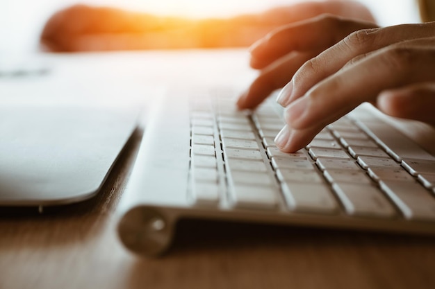 Photo cropped hands typing on keyboard in home