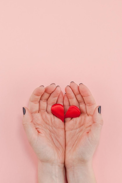 Photo cropped hands of woman holding broken heart shape against pink background